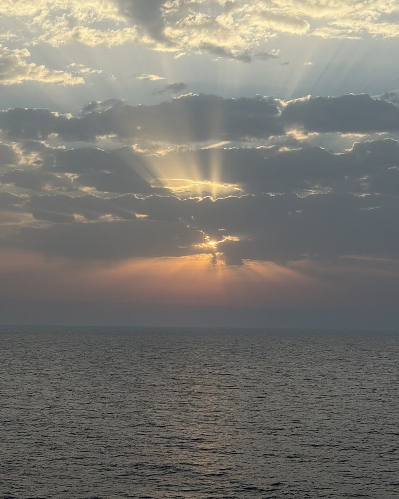 Sunbeams breaking through clouds over the open sea